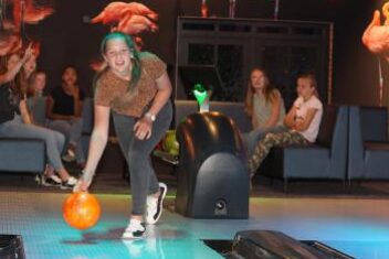 meisje gooit bowlingbal over bowlingbaan