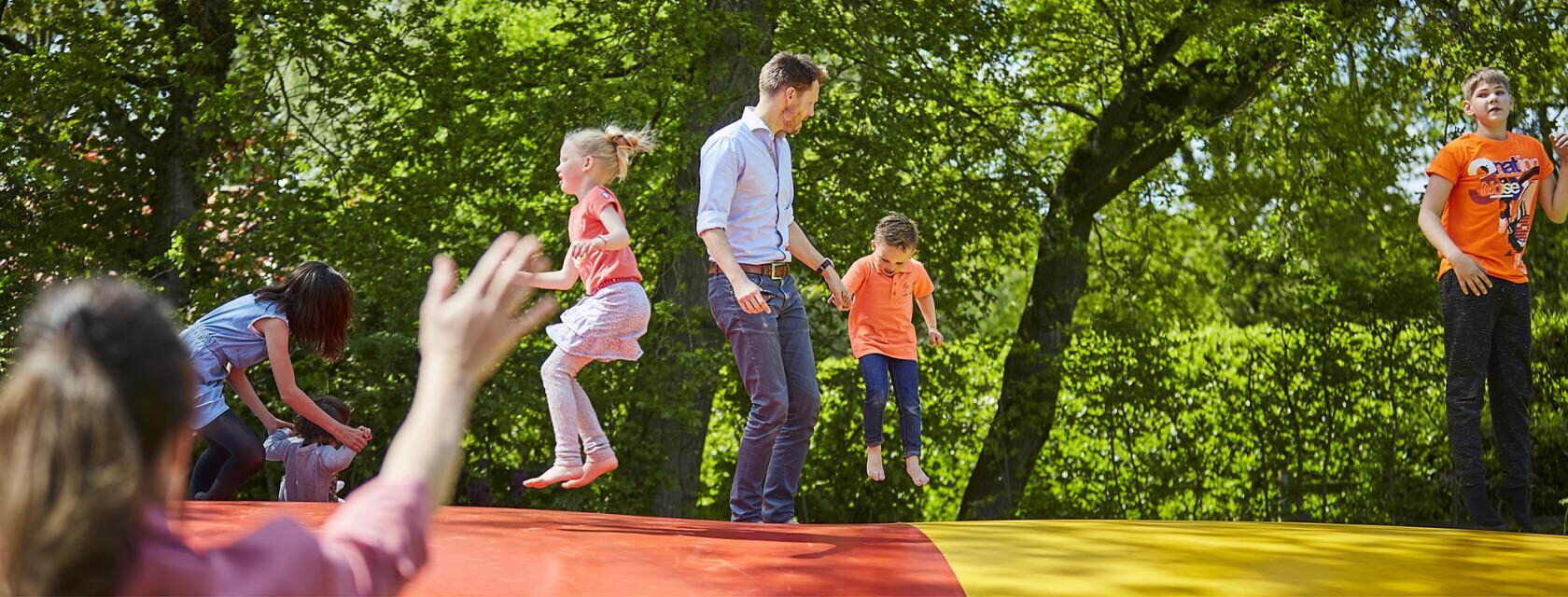 man en kinderen springen op springkussen